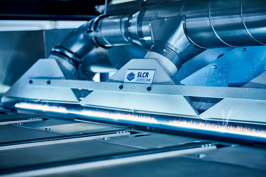 Die durch die Strukturierung mit dem Laser erzeugten Mikro- und Nanostrukturen erhöhen die spezifische Oberfläche, was zu einer besseren mechanischen Verankerung der Beschichtung führt. Hier ein Blick in die Anlage bei laufender Bearbeitung.