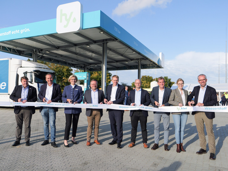 Schleswig-Holsteins Ministerpräsident Daniel Günther (Mitte) durchschneidet das Band zur feierlichen Eröffnung der Tankstelle.