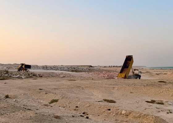 Erdarbeiten in Duqm. Die Küstenwüste ähnelt einer Mondlandschaft. Im Hintergrund ist das Arabische Meer zu sehen, das außerhalb der Straße von Hormus liegt. 